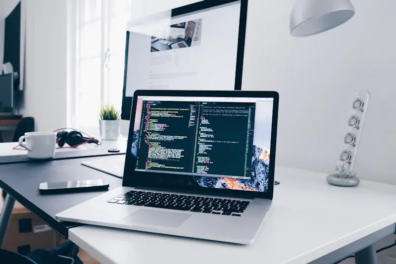 Laptop on a desk showing website code in a creative workspace